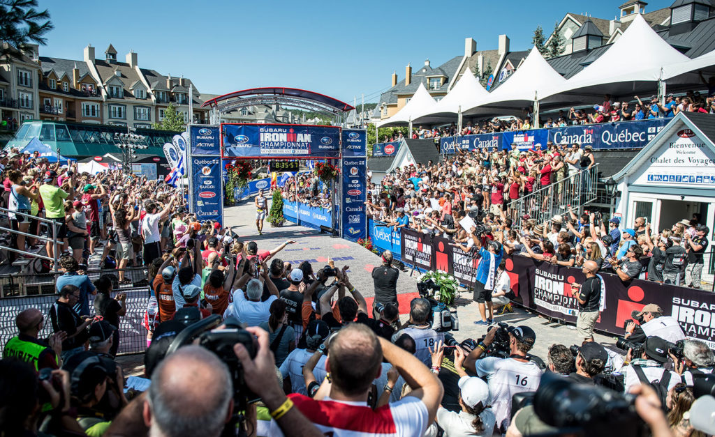 Cyclists race through a crowded finish line with enthusiastic spectators.