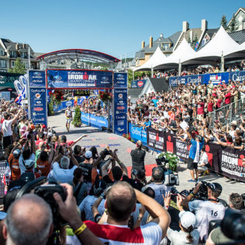 Cyclists race through a crowded finish line with enthusiastic spectators.