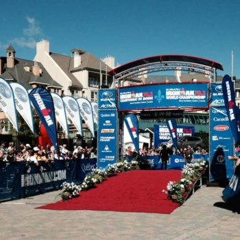 Outdoor event stage with banners and a red carpet under clear skies.