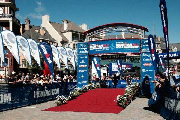 Outdoor event stage with banners and a red carpet under clear skies.
