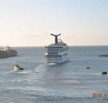 A cruise ship sailing on the sea with smaller boats nearby.