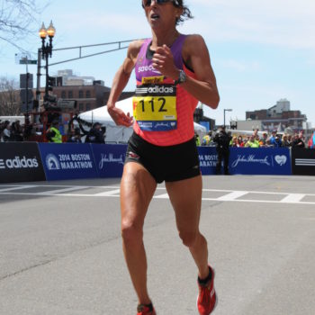 Runner in pink tank top competing in a city marathon.