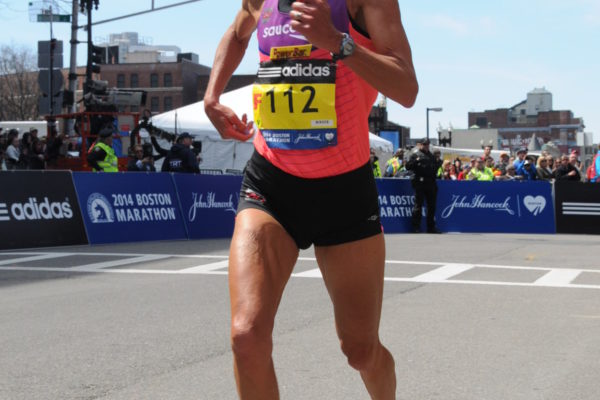 Runner in pink tank top competing in a city marathon.