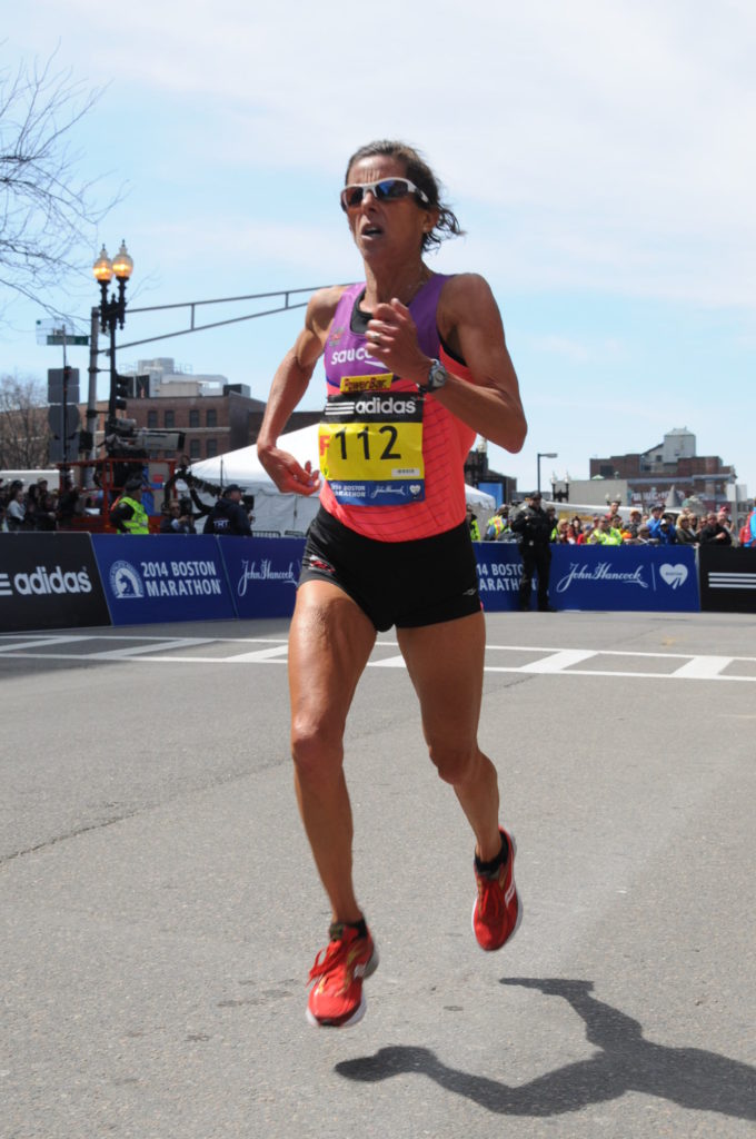 Runner in pink tank top competing in a city marathon.