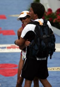 Two athletes embracing after a race near a finish line.