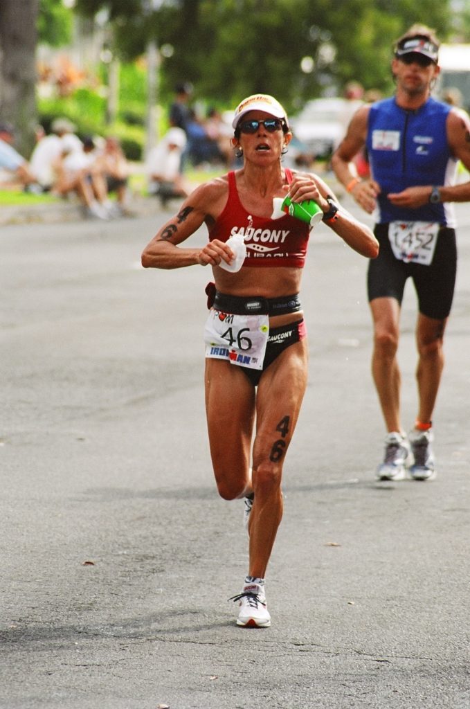 Female athlete running in a marathon race on a city street.