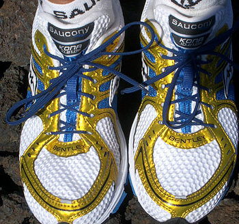 Pair of white and yellow running shoes with blue laces.