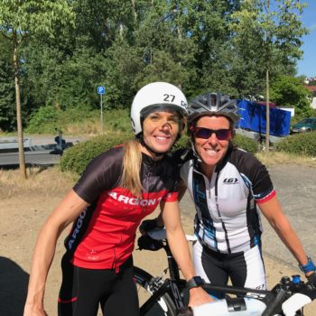 Two cyclists smiling and posing outdoors with their bikes.
