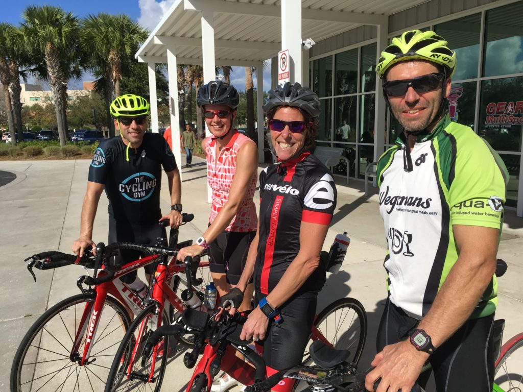Four cyclists posing with their bikes in bright gear.