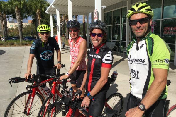 Four cyclists posing with their bikes in bright gear.