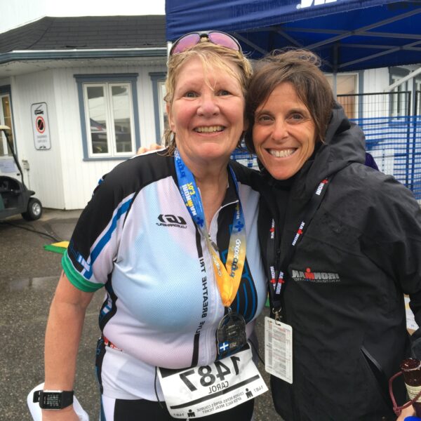 Two smiling women posing together outdoors, one with a race bib.