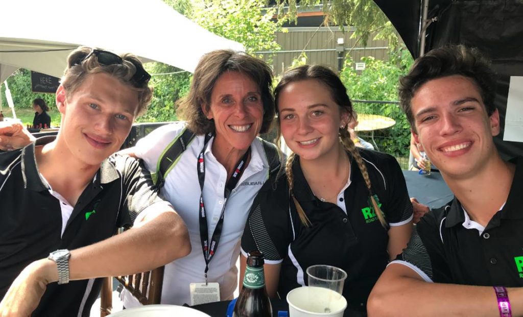 Four people smiling around a table outdoors with drinks.