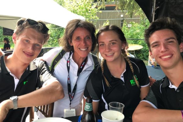 Four people smiling around a table outdoors with drinks.