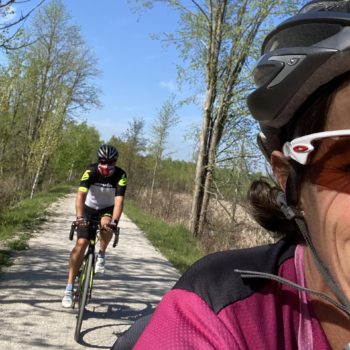 Two cyclists riding on a sunny forest trail.