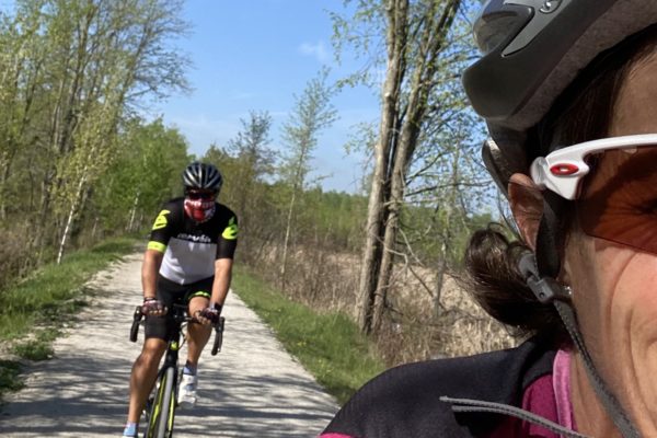 Two cyclists riding on a sunny forest trail.