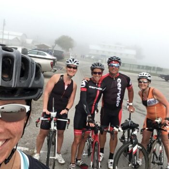 Group of motorcyclists posing with their bikes in a parking lot.